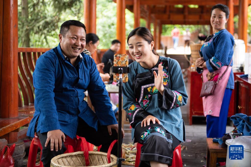 在湖南湘西十八洞村,十八洞村扶贫队长麻辉煌(左)与返乡老员工施林娇(中)一起直播推销土特产(2020年5月15日摄)。新华社记者 陈思汗 摄